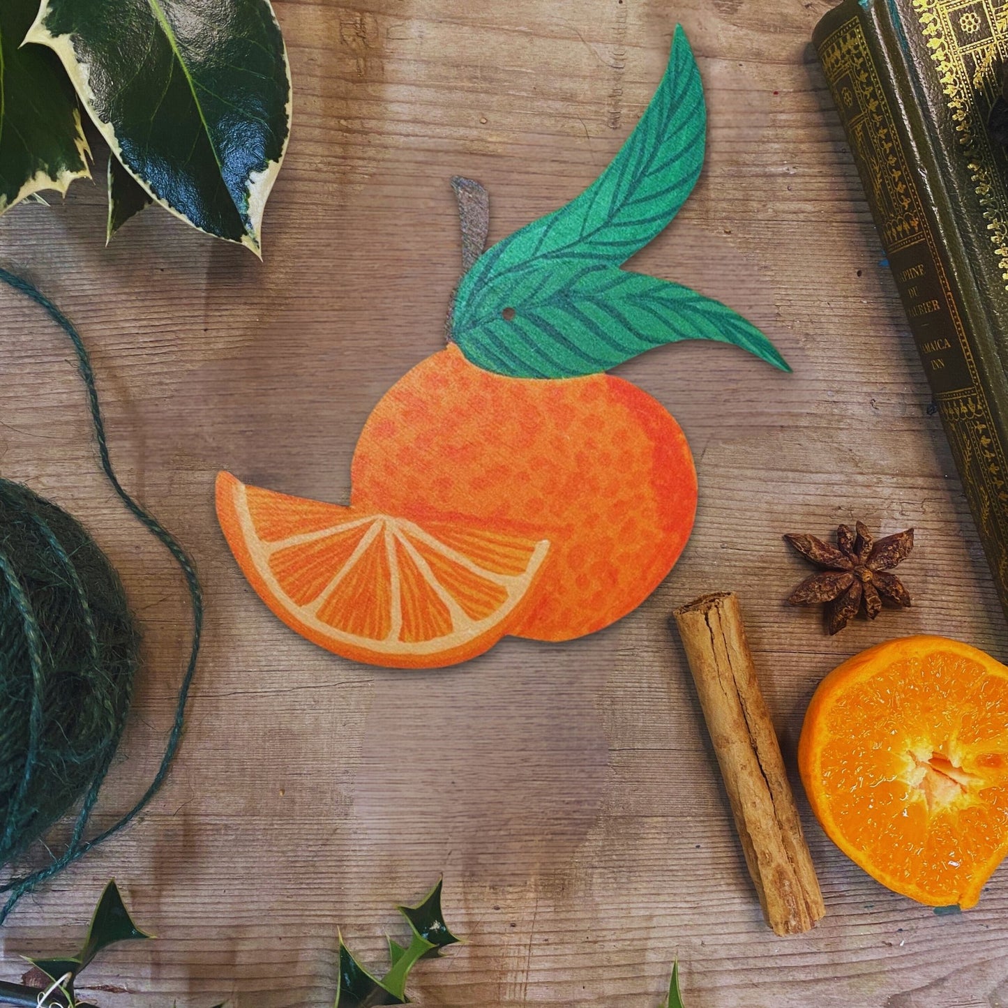 Decorative orange and slice on a wooden surface with cinnamon stick and star anise.