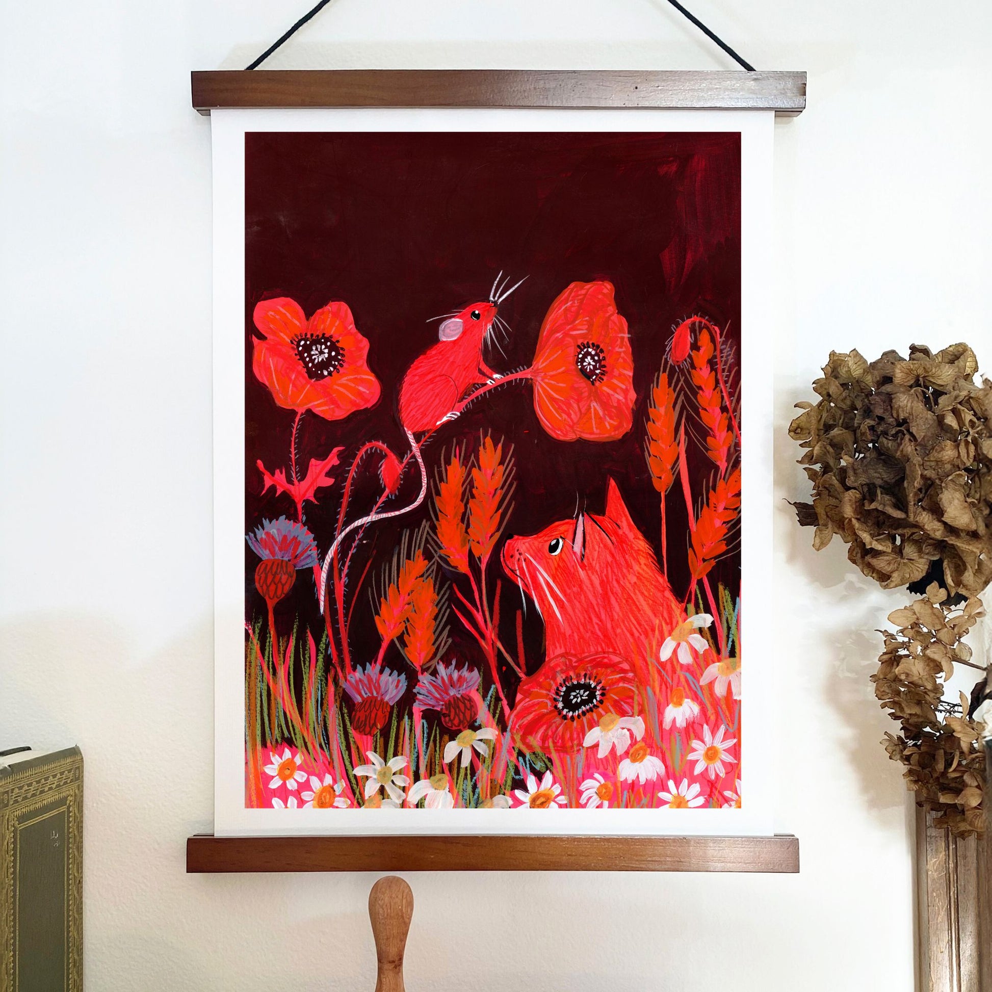 Framed artwork with red birds and flowers on a white wall