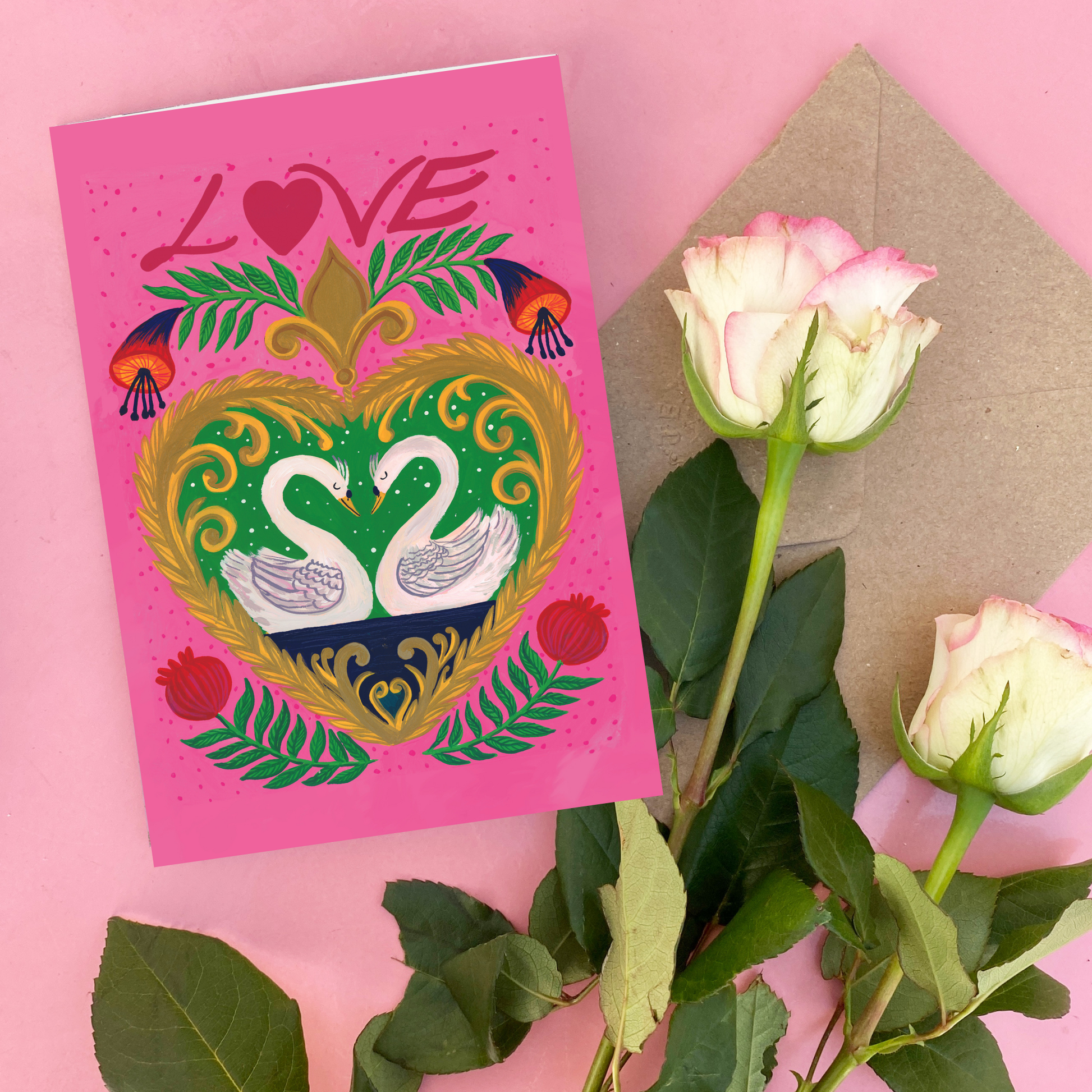 Greeting card with swans and 'LOVE' text on a pink background with flowers and an envelope.