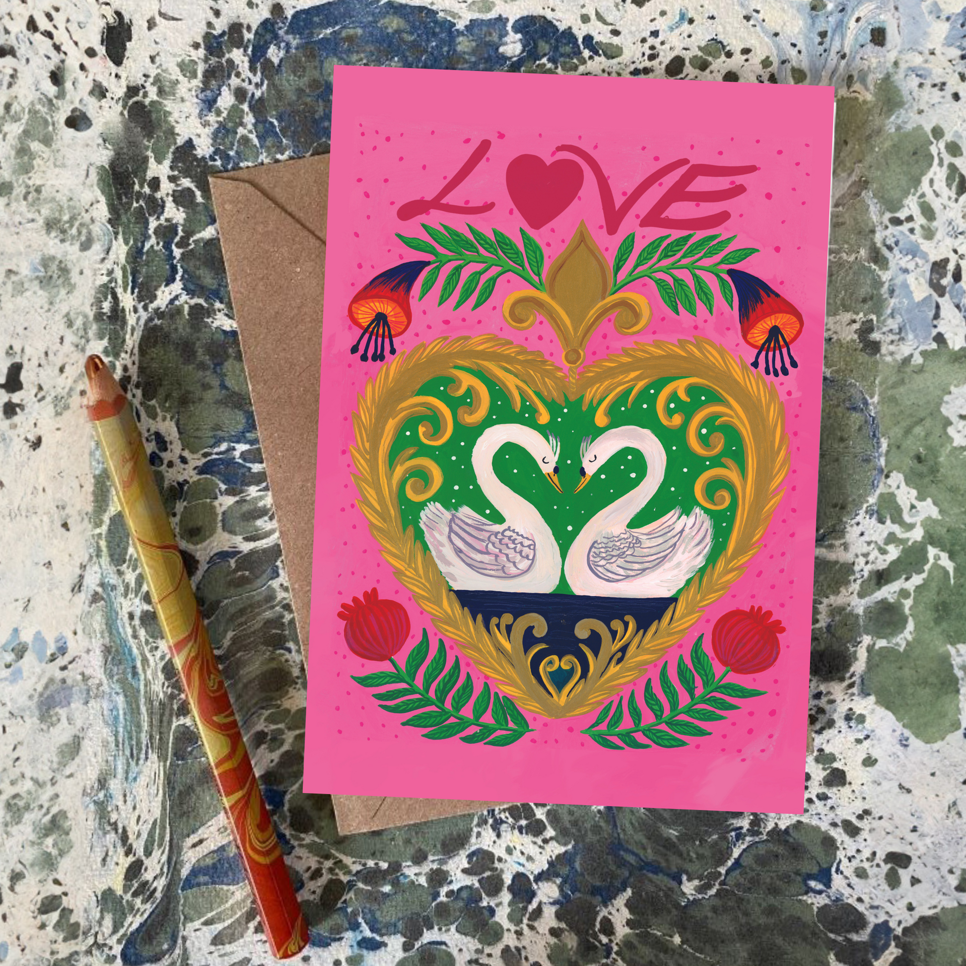 Greeting card with decorative heart design and 'LOVE' text on a textured surface with a pen.