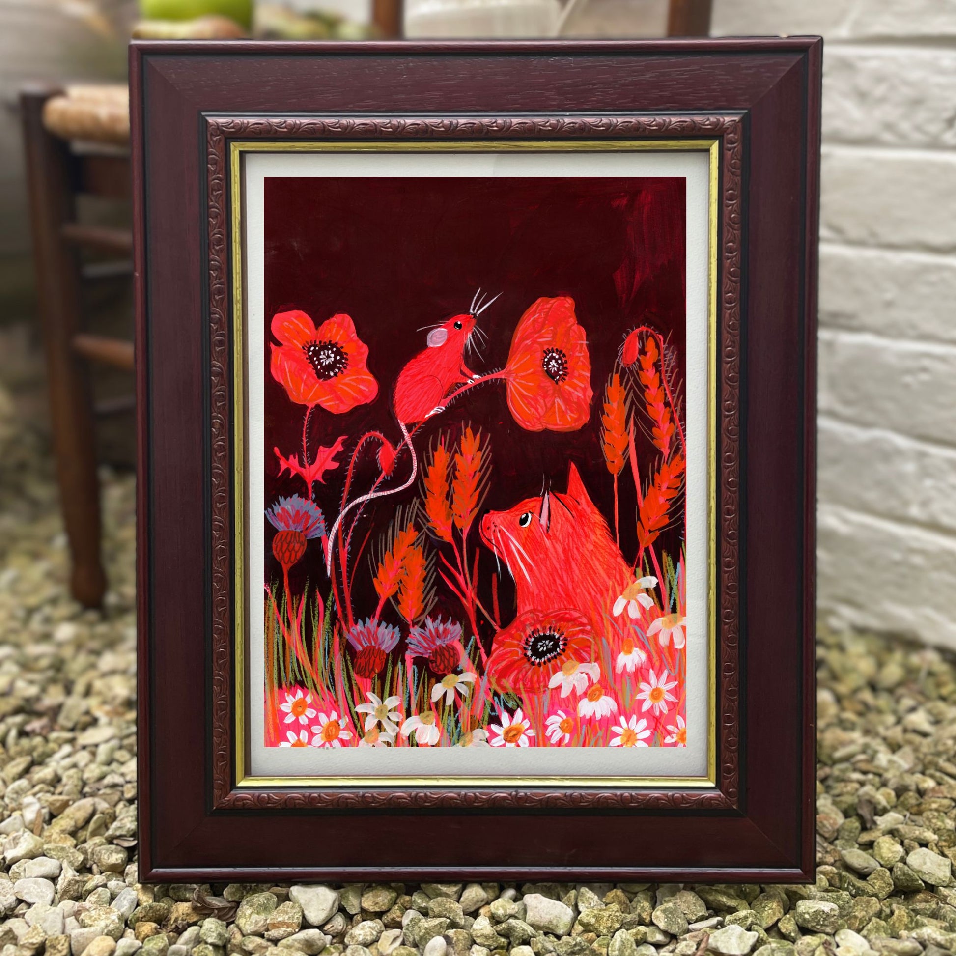 Framed artwork with red animals and flowers on a dark background