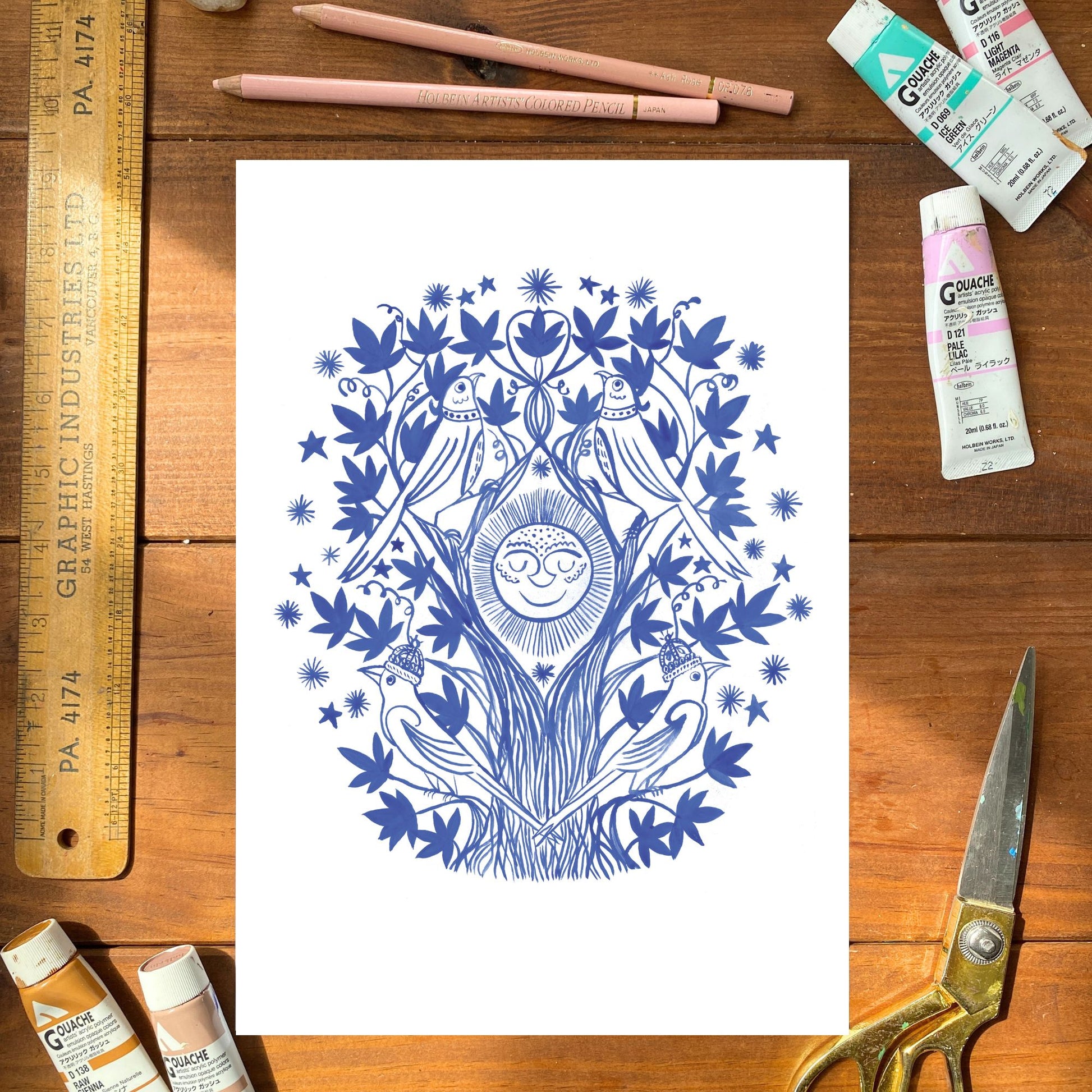Blue and white artwork on a wooden surface with art supplies