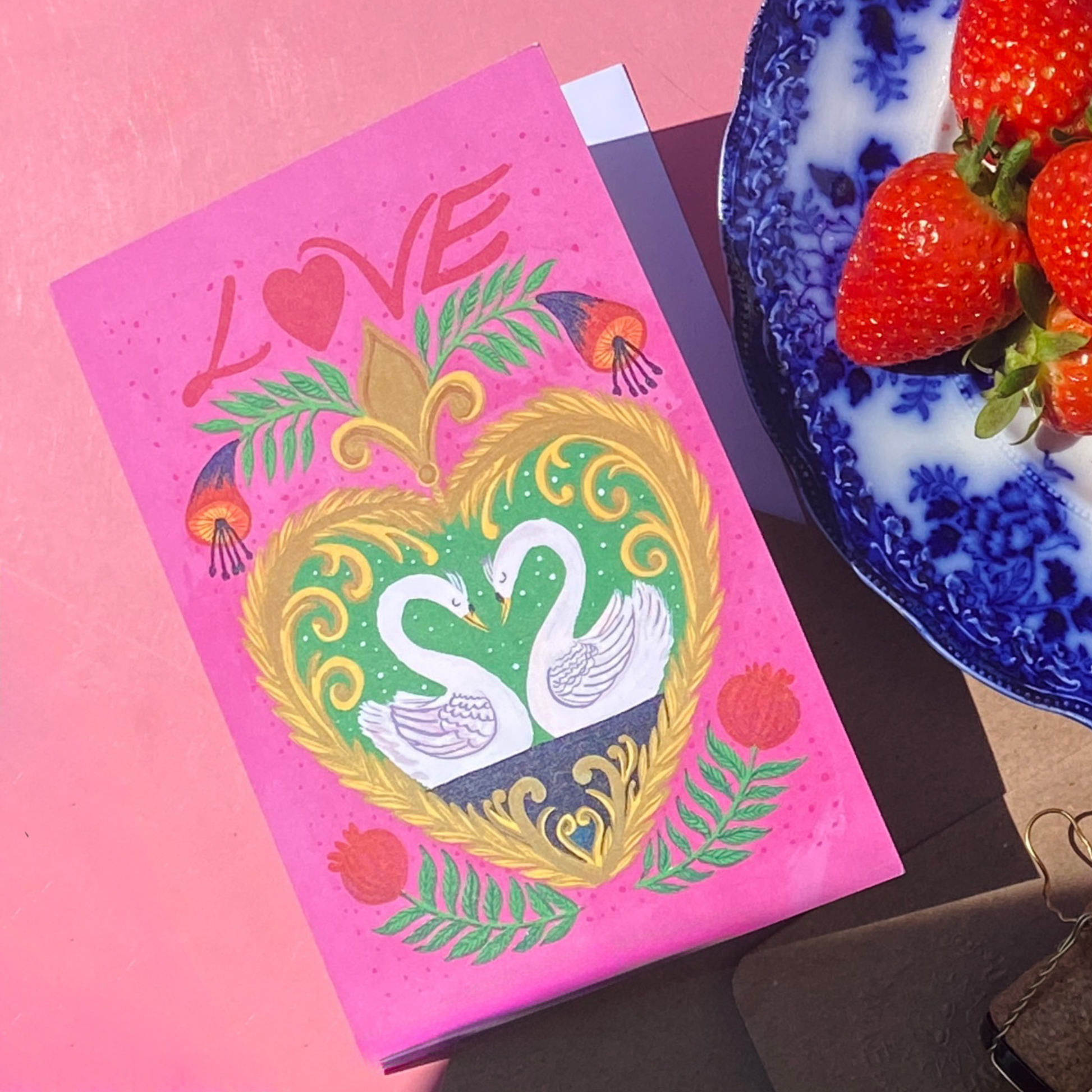 Pink Card with swan design and 'LOVE' text on a pink background with strawberries.