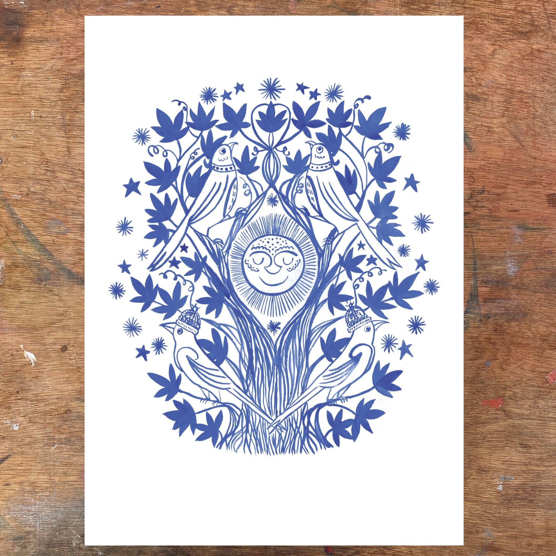 Blue and white decorative print with birds and a sun on a wooden surface