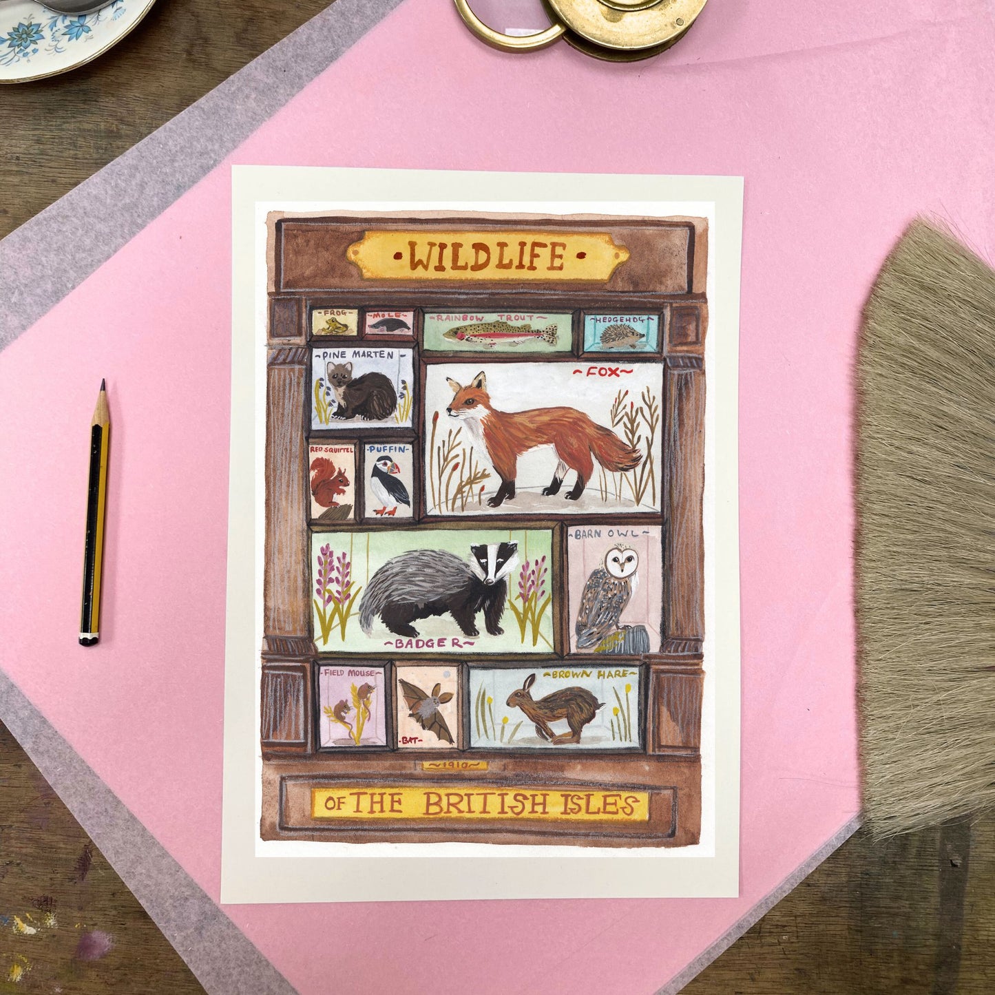 Illustrated card with British wildlife design on a pink surface with a pencil.
