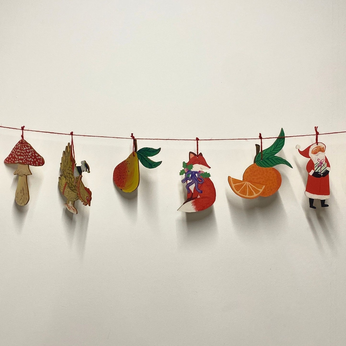 Decorative string with colorful paper cutouts of a fox, bird, mushroom, and other shapes on a white background.