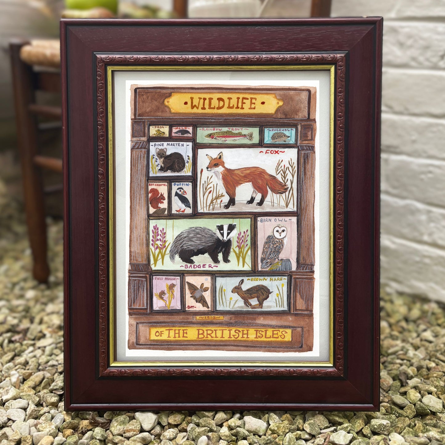 Framed artwork of wildlife illustrations with a wooden frame on a stone surface.