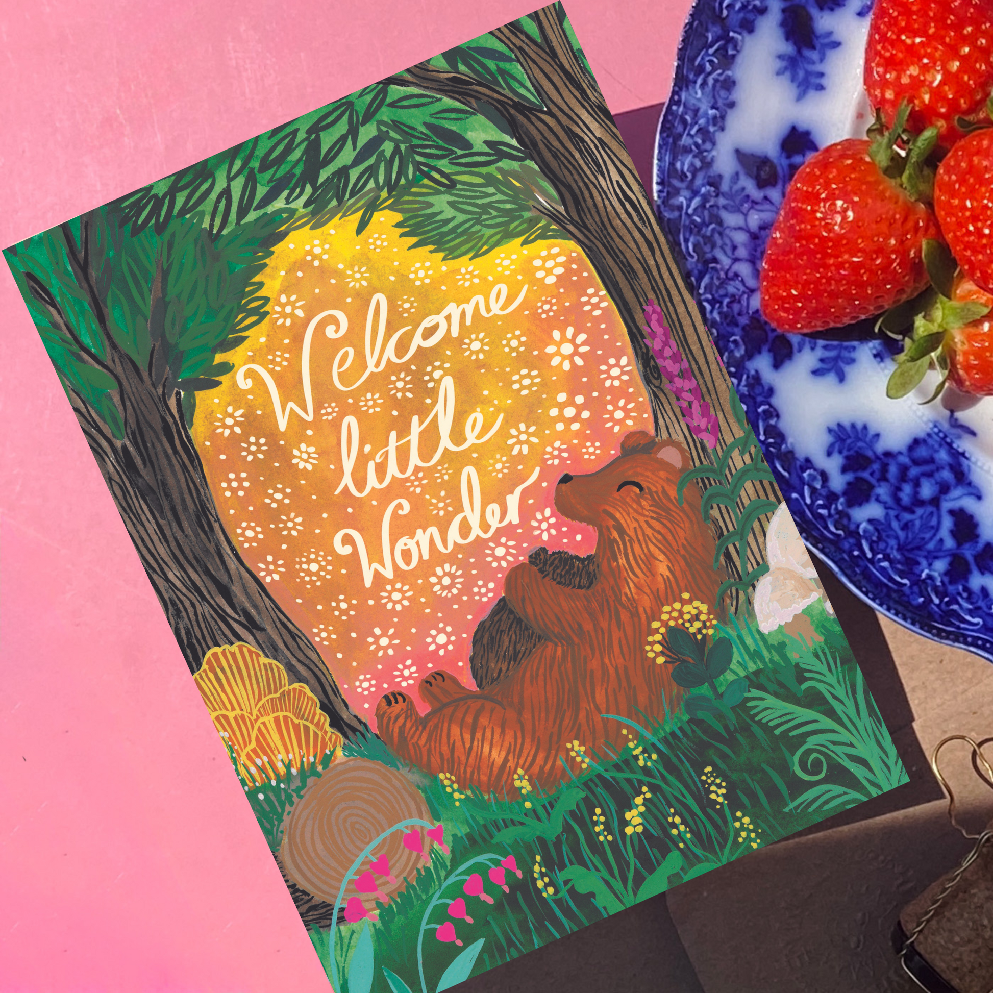 Illustrated card with a bear and text 'Welcome little wonder' on a pink background with  berrys
